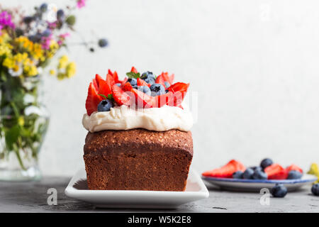 Estate dessert con fragole e mirtilli. Torta di pane con glassa di crema di burro e guarnita con fresche e mature colorata estate frutti e bacche, sel Foto Stock