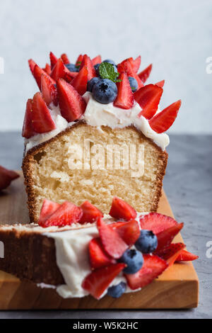 Estate dessert con fragole e mirtilli. Crema di burro berry ciambellone con slice e colorati di frutti e bacche sulla parte superiore, il fuoco selettivo, chiudi Foto Stock