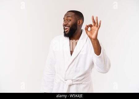 Giovane africano in accappatoio preparare per la cura della pelle che mostra ok dito segno. Le emozioni umane concept Foto Stock