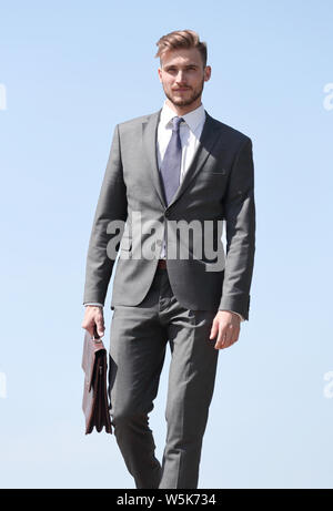 Fiducioso imprenditore con valigetta in pelle in avanti passo-passo Foto Stock