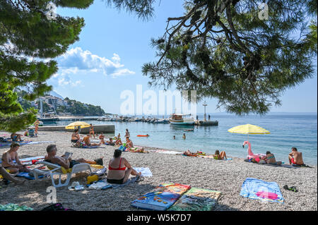 Il turista a godere la spiaggia a Brela. La riviera di Makarska in Croazia è famosa per le sue belle spiagge di ciottoli e acqua cristallina. Foto Stock