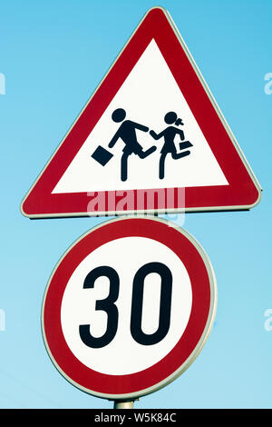 Il traffico su strada segno attenzione bambini, 30 km segnale di limite di velocità nei pressi della scuola Foto Stock