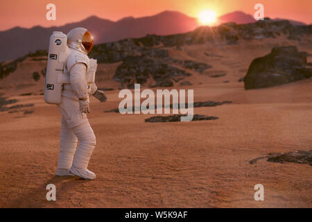 Astronauta sul pianeta Marte, camminando attraverso un paesaggio deserto Foto Stock