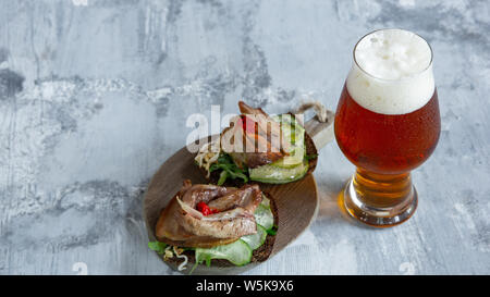 Bicchiere di birra sulla pietra bianca di sfondo della tabella. Drink e snack a base di carne sono preparati per una grande festa. Concetto di bevande, divertente, cibo, celebrando, sale riunioni, Oktoberfest. Foto Stock