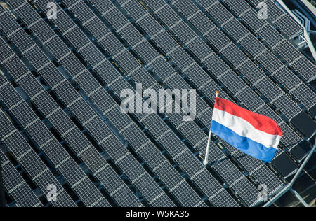 Dutch bandiera tricolore su un nero cella solare tetto di tegole shot da sopra per uso come un sfondo astratto Foto Stock