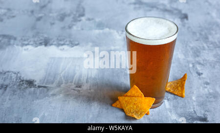 Bicchiere di birra chiara sulla pietra bianca dello sfondo. Alcol freddo drink e spuntini sono preparati per una grande festa. Concetto di bevande, divertente, cibo, celebrando, sale riunioni, Oktoberfest. Foto Stock