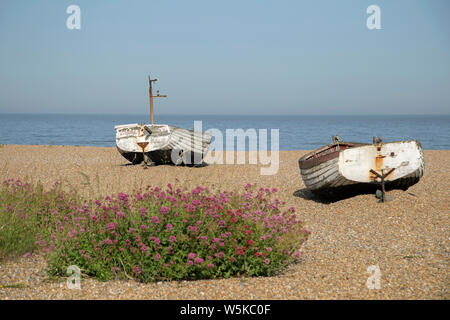 Due imbarcazioni a remi bloccati sulla spiaggia di ciottoli a Alburgh, Suffolk, Inghilterra su una luminosa giornata di sole. Foto Stock