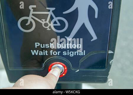 Un maschio di mano spinge un pulsante su un attraversamento pedonale Foto Stock