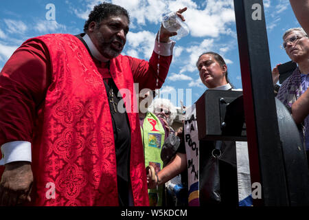 El Paso, Texas, Stati Uniti d'America. 29 Luglio, 2019. REV. Il DR. WILLIAM J. BARBIERE II, versa una bottiglia di acqua simbolico che parla ad un microfono ad agenti a El Paso centro di elaborazione durante la prima 'moral lunedì a confini' interfaith protesta contro la Trump dell amministrazione di politiche in materia di immigrazione al di fuori del El Paso Processing Center di El Paso, Texas. Credito: Joel Angelo Juarez/ZUMA filo/Alamy Live News Foto Stock