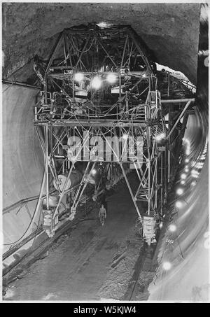 Pistola di calcestruzzo carrello utilizzato in immissione 110 grado top-arch concreta nel tunnel di diversione, campo di applicazione e il contenuto: fotografia dal volume due di una serie di album di foto per documentare la costruzione della Diga di Hoover, Boulder City, Nevada. Piena didascalia della foto si legge: Calcestruzzo gun carrello utilizzato in immissione 110 grado top-arch concreta nel tunnel di diversione. Il calcestruzzo viene trasportata dal carrello in discarica-secchi in posizione sotto il carrello, issato al ponte superiore mediante gru a ponte operanti su testa, oggetto di dumping nelle tramogge e costretti in forma mediante aria compressa attraverso due 8 pollici di acciaio e tubi di gomma. Due unità della pistola Foto Stock