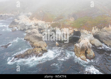 Visto dall'occhio di un uccello, le fredde acque dell'Oceano Pacifico lavare contro il roccioso ancora bellissima costa sud di Monterey in California del Nord. Foto Stock