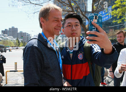 Manager del calcio tedesco e pundit Jurgen Klinsmann, sinistra, prende selfies con un ventilatore durante una visita a Pechino, Cina, 14 aprile 2019. Mentre su un visi Foto Stock