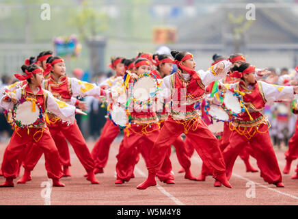 Studenti della scuola primaria in costumi tradizionali prendere parte a una riunione di sport in una scuola primaria nella città di Hohhot, nord cinese della Mongolia interna Foto Stock