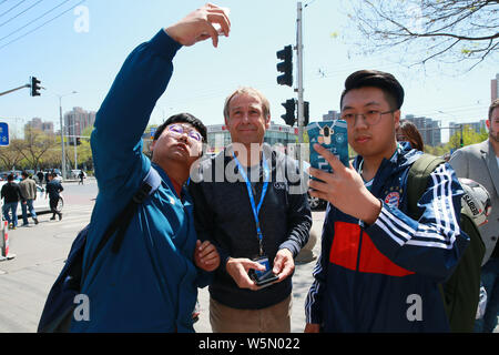 Manager del calcio tedesco e pundit Jurgen Klinsmann, sinistra, prende selfies con ventole durante una visita a Pechino, Cina, 14 aprile 2019. Durante una visita Foto Stock