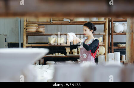 La porcellana cinese craftswoman Xu Shan rende porcellana e ceramica presso la sua officina nella città di Jingdezhen, Cina orientale della provincia di Jiangxi, 10 aprile 2019. Foto Stock