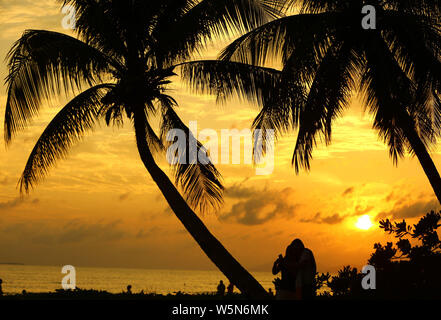 Persone godere il tempo libero tra la luminosità del tramonto sul mare nella città di Sanya, Cina del sud della provincia di Hainan, 22 aprile 2019. Foto Stock