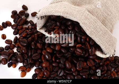 Foto di chicchi di caffè fuoriuscita dal sacco di iuta o marsupio shot su sfondo bianco Foto Stock