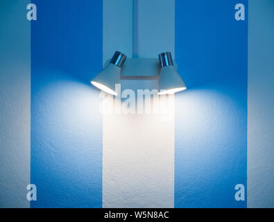 Lampada da parete in bianco e blu a strisce sullo sfondo della parete con copia spazio. Foto Stock