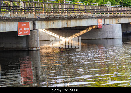 Un cartello bilingue avverte i barcaioli sulle rive di un fiume, in inglese e in francese e non per passare sotto un ponte al di sopra di una diga aperta. Foto Stock