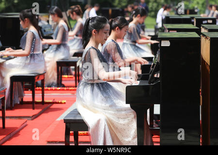 I partecipanti suonare il pianoforte formando la forma di 70 per celebrare il settantesimo anniversario della fondazione della Repubblica popolare cinese durante una competizione in comunicazione Unive Foto Stock