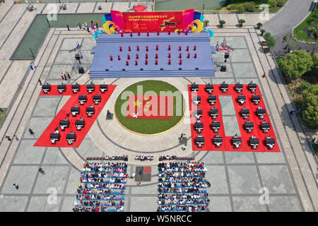 I partecipanti suonare il pianoforte formando la forma di 70 per celebrare il settantesimo anniversario della fondazione della Repubblica popolare cinese durante una competizione in comunicazione Unive Foto Stock
