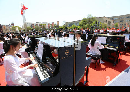 I partecipanti suonare il pianoforte formando la forma di 70 per celebrare il settantesimo anniversario della fondazione della Repubblica popolare cinese durante una competizione in comunicazione Unive Foto Stock