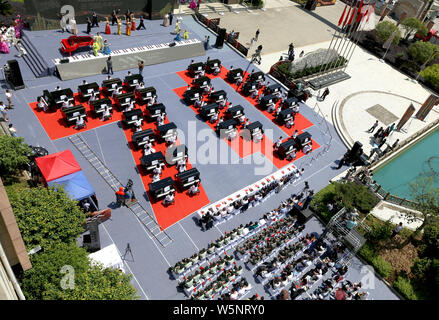 I partecipanti suonare il pianoforte formando la forma di 70 per celebrare il settantesimo anniversario della fondazione della Repubblica popolare cinese durante una competizione in comunicazione Unive Foto Stock