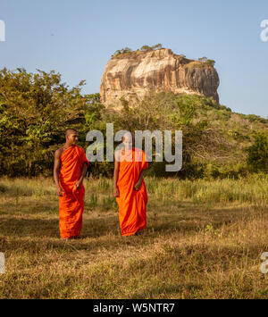 Negombo, Sri Lanka - 2019-03-22 - i monaci a piedi nel campo di erba con Roccia di Sigiriya in background. Foto Stock