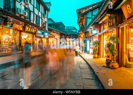 --FILE--turisti a piedi passato negozi lungo la strada in Ciqikou antica città, Chongqing, la Cina, il 13 dicembre 2018. Foto Stock