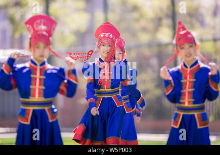 Il cinese studenti primari in costumi tradizionali e indossando il taglio della carta posa headwears presso una scuola in Huhhot, città del nord della Cina Foto Stock