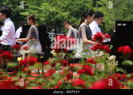 I partecipanti suonare il pianoforte formando la forma di 70 per celebrare il settantesimo anniversario della fondazione della Repubblica popolare cinese durante una competizione in comunicazione Unive Foto Stock