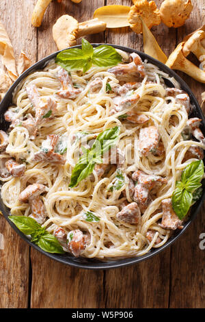 Delizioso Spaghetti con fried finferli in salsa di formaggio cremoso close-up su una piastra sul tavolo. Verticale in alto vista da sopra Foto Stock