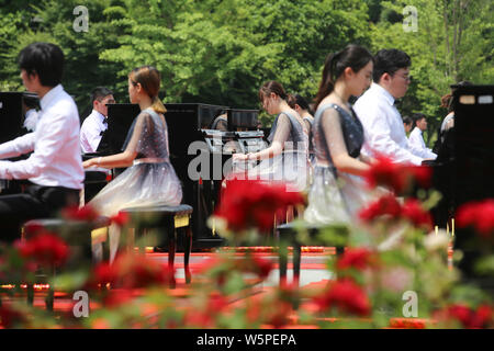 I partecipanti suonare il pianoforte formando la forma di 70 per celebrare il settantesimo anniversario della fondazione della Repubblica popolare cinese durante una competizione in comunicazione Unive Foto Stock