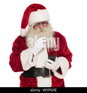 Ritratto della vecchia santa inviando un sms mentre in piedi su sfondo bianco e guardando verso il basso al telefono Foto Stock