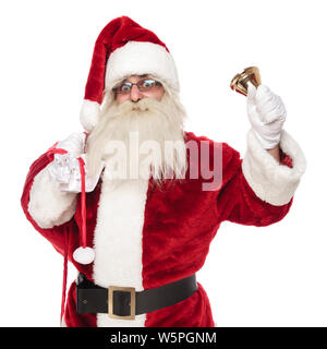 Ritratto di vecchio merry santa azienda doni sacco e campana che squilla mentre in piedi su sfondo bianco Foto Stock