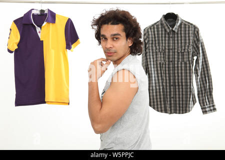 Ritratto di un uomo con polo e camicia appesa dietro di lui Foto Stock