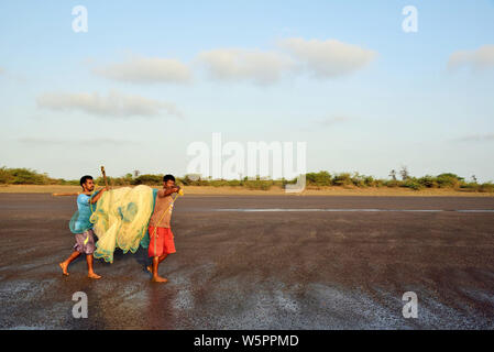 I pescatori che trasportano le reti da pesca Surwada beach Valsad Gujarat India Asia Foto Stock