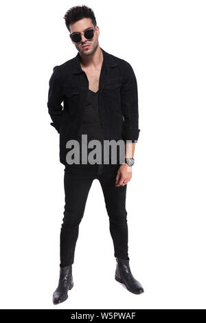 Bel uomo macho vestiti di nero e con occhiali da sole in piedi su sfondo  bianco con una mano dietro la schiena a piena lunghezza immagine Foto stock  - Alamy