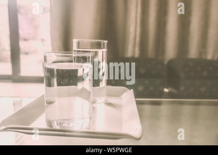 2 bicchieri di acqua potabile alla tabella. Luce del sole di mattina proveniente dalla finestra. Due bicchieri di pura acqua calda dopo svegliarsi al mattino. Buona abitudine mattutina Foto Stock