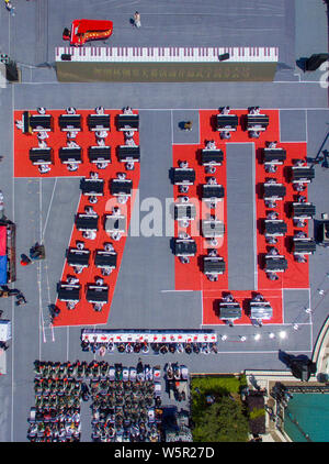 I partecipanti suonare il pianoforte formando la forma di 70 per celebrare il settantesimo anniversario della fondazione della Repubblica popolare cinese durante una competizione in comunicazione Unive Foto Stock