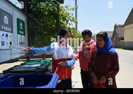 Un volontario cinese introduce immondizia cernita per gli abitanti di un villaggio nel villaggio Dongchu, Rongcheng city, est della Cina di provincia di Shandong, 4 giugno 2019. Varie Foto Stock