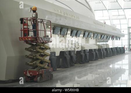 Una costruzione cinese lavoratore mette i tocchi finali sulla facciata di contatori di compagnie aeree nel terminale di Pechino Daxing Aeroporto Internazionale della BEI Foto Stock