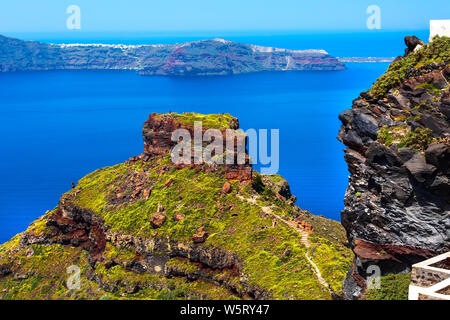 Santorini, Grecia panorama con Skaros rock, grande pietra vulcanica e caldera mare, fiori e isola di Vulcano sullo sfondo Foto Stock