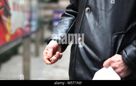 --FILE--un uomo anziano fuma davanti ad un ospedale nella città di Hangzhou, a est della Cina di provincia dello Zhejiang, 2 gennaio 2019. Il fumo ha subito un declino su Foto Stock