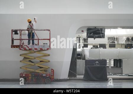 Una costruzione cinese lavoratore mette i tocchi finali sulla facciata di contatori di compagnie aeree nel terminale di Pechino Daxing Aeroporto Internazionale della BEI Foto Stock