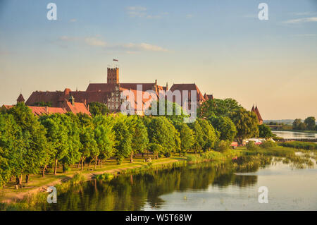 Il Castello dell'Ordine Teutonico in Malbork, Polonia con il fiume di Nogat shore. Castello del XIII secolo è il più grande castello nel mondo misurata per mezzo di una LAN Foto Stock