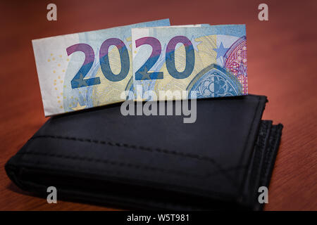 Chiusura del portafoglio nero sul tavolo di legno con le banconote in euro Foto Stock