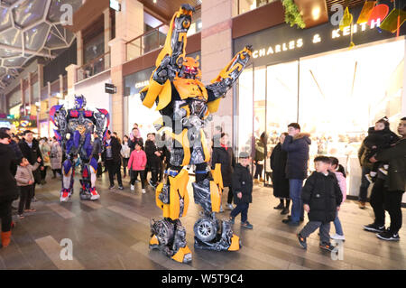 Uno studente di college che indossa un due-metro-high life-size replica di Bumblebee è circondato da clienti presso un centro commerciale per lo shopping a Xi'an City, Cina nord-occidentale Foto Stock