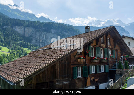 Lauterbrunnen, Svizzera - 21 Luglio 2019: Tipico edificio svizzero e le montagne sullo sfondo Foto Stock