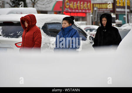 I pedoni a piedi passato auto coperti di neve durante una nevicata nella città di Yantai, est della Cina di provincia di Shandong, 7 dicembre 2018. Un ondata di freddo br Foto Stock